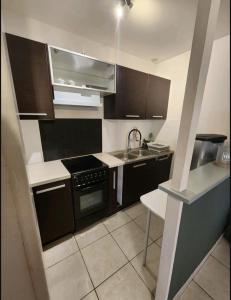 a small kitchen with black cabinets and a sink at Maison de ville proche Le Portel 2 chambres in Outreau
