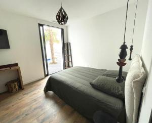 ein Schlafzimmer mit einem Bett und einem großen Fenster in der Unterkunft LA PALMERAIE in Châtelaillon-Plage
