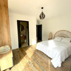 Schlafzimmer mit einem weißen Bett und Holzboden in der Unterkunft LA PALMERAIE in Châtelaillon-Plage