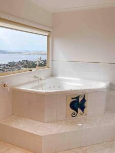 y baño con bañera y ventana. en Millions View - Hobart, en Sandy Bay