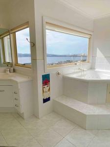 baño con bañera, lavabo y ventana en Millions View - Hobart, en Sandy Bay
