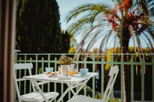 a white table and chairs on a balcony with palm trees at Angolo a Corte in Pietrasanta