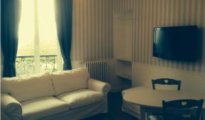 a living room with a couch and a table and a television at La Maison de Silly in Silly-en-Gouffern