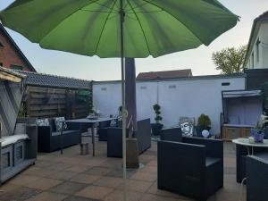 a green umbrella on a patio with tables and chairs at Unterkunft mit Wohlfühleffekt und Flair in Rehburg-Loccum