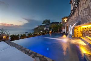 uma piscina com vista para o oceano à noite em Amore Rentals - Villa dei Sogni em Massa Lubrense