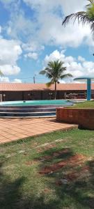 a swimming pool in front of a building with palm trees at Vila Real in São Mateus
