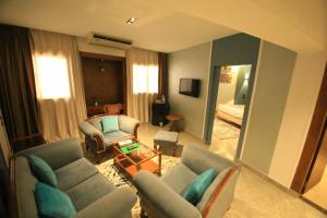 a living room with a couch and chairs and a mirror at Green House Hotel in As Suways