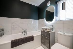 a bathroom with a tub and a toilet and a sink at Luxury home that sleeps up to 8 adults and 6 children - hot tub and parking for 4 cars in Bury Saint Edmunds