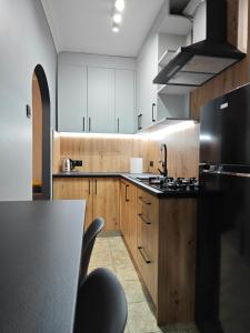 a kitchen with wooden cabinets and a black refrigerator at Medyka Loft in Medyka