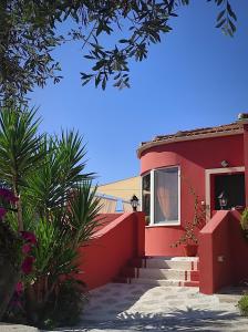 una casa roja con una pared roja y algunas plantas en Stella Rossa, en Áno Garoúna