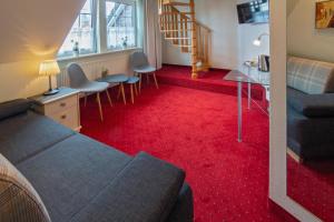 uma sala de estar com um sofá e um tapete vermelho em Hotel am Elisabethufer em Jever
