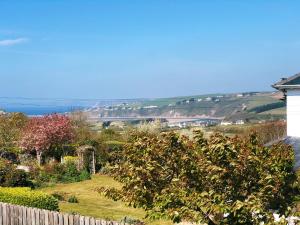 a garden with a fence and a view of the water at Bantham Beach Pad in Thurlestone
