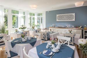 une salle à manger avec des tables et des chaises blanches dans l'établissement Hotel am Elisabethufer, à Jever