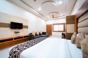 ein Hotelzimmer mit einem Bett und einem Flachbild-TV in der Unterkunft Hotel Royal Palace in Sāgar