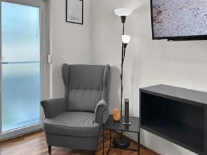 a living room with a chair and a television at Relax Oasis with 65 SmartTV, Kitchen and Balcony in Duisburg