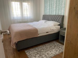 1 dormitorio con 1 cama con ventana y alfombra en Zeus apartman, en Hiseti