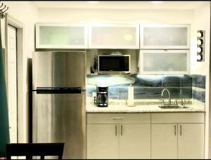 a kitchen with a stainless steel refrigerator and white cabinets at Seashell 4 in Boynton Beach