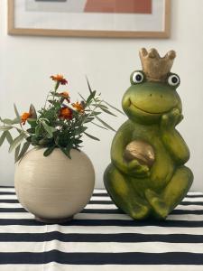 Une grenouille portant une couronne à côté d'un vase de fleurs dans l'établissement Lola’s Apartment, à Durrës