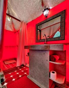 a red bathroom with a sink and a mirror at Luxury Sahara Camp in Merzouga
