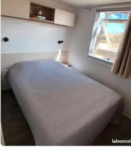 uma cama branca num quarto com uma janela em Mobil home Canet Roussillon 4 étoiles le Mar Estang 8 pers em Canet-en-Roussillon