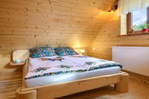 sypialnia z łóżkiem w drewnianej ścianie w obiekcie Tylickie Chałupy w mieście Tylicz