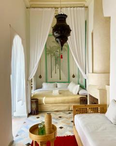 a bedroom with two beds and a table and a chandelier at Riad Tizwa Marrakech in Marrakech