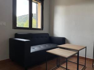 ein Sofa und einen Tisch in einem Zimmer mit Fenster in der Unterkunft Apartamentos Los Pocillos in Gargantilla del Lozoya y Pinilla de Buitrago