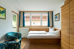 a bedroom with a bed and a chair and a window at Alpenhotel Erika in Ischgl
