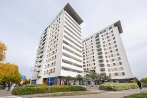 a tall white building with people walking in front of it at Metro Imielin 13th Floor Apartment by BookingHost in Warsaw