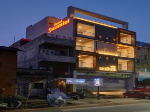 a building with a neon sign on the side of it at Hotel Swamini Kolhapur in Kolhapur