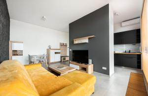 a living room with a couch and a kitchen at Metro Imielin 13th Floor Apartment by BookingHost in Warsaw