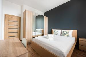a bedroom with a large bed and a mirror at Metro Imielin 13th Floor Apartment by BookingHost in Warsaw