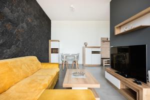 a living room with a couch and a tv at Metro Imielin 13th Floor Apartment by BookingHost in Warsaw