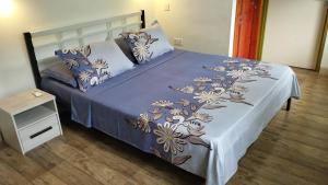 a bed with a blue comforter and pillows at Dovass Self Catering Apartments in Takamaka