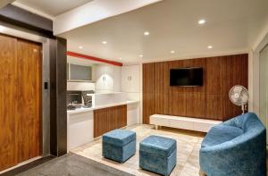 a living room with a blue chair and a kitchen at Hotel Swamini Kolhapur in Kolhapur