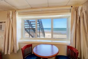 Habitación con mesa, sillas y ventana con playa. en Atlantic Oceanfront Hotel, Wells Beach, en Wells