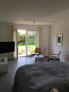 Schlafzimmer mit einem Bett und einem Fenster mit Stühlen in der Unterkunft Nije Haven Bed & Breakfast in Wrixum