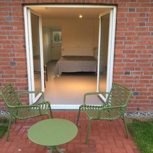 2 grüne Stühle und ein Tisch auf der Terrasse in der Unterkunft Nije Haven Bed & Breakfast in Wrixum