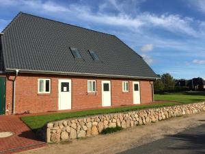 a brick house with white doors and a stone wall at Nije Haven Bed & Breakfast in Wrixum