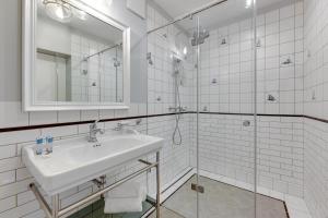 a white bathroom with a sink and a shower at Historical Townhouse by Blue Mandarin in Gdańsk