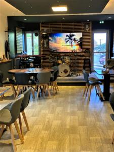 a room with tables and chairs and a large screen at Le 120 - Groupe Logis Hotels - Ex Auberge la Terrasse in La Châtaigneraie