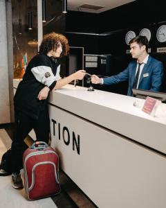 une femme debout à côté d'un comptoir avec une valise dans l'établissement The Diamond Hotel Baku, à Baku