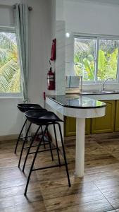 a kitchen with a glass table and two stools at Dovass Self Catering Apartments in Takamaka