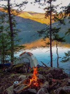 a tent and a camp fire next to a lake at glamping camping kamping in Ungasan