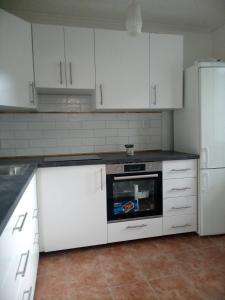 a kitchen with white cabinets and a stove and refrigerator at Bibi Apartment in Martin