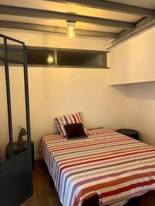 een slaapkamer met een bed met een gestreepte deken bij Loft lumineux en centre ville in Sète