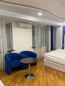 a bedroom with a bed and a table and blue chairs at Grand House Hotel & Zipline Kapan, Armenia in Kapan