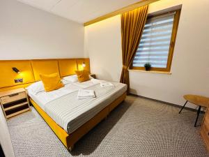 Un dormitorio con una cama con almohadas amarillas y una ventana en Apartamenty Czerwone Korale, en Cielimowo