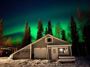 a house in the snow with the aurora in the sky at RukaTupa Motelli in Ruka