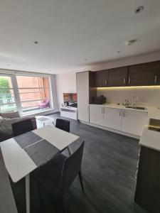 a living room with a table and a kitchen at Rent Luxuri - Luxury 2 bed Apartment in Leicester